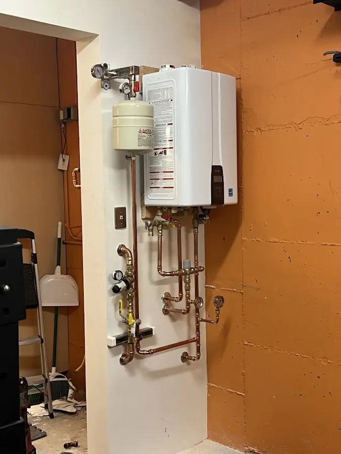 Plumbing technician inspecting water heater connections in Kings Park